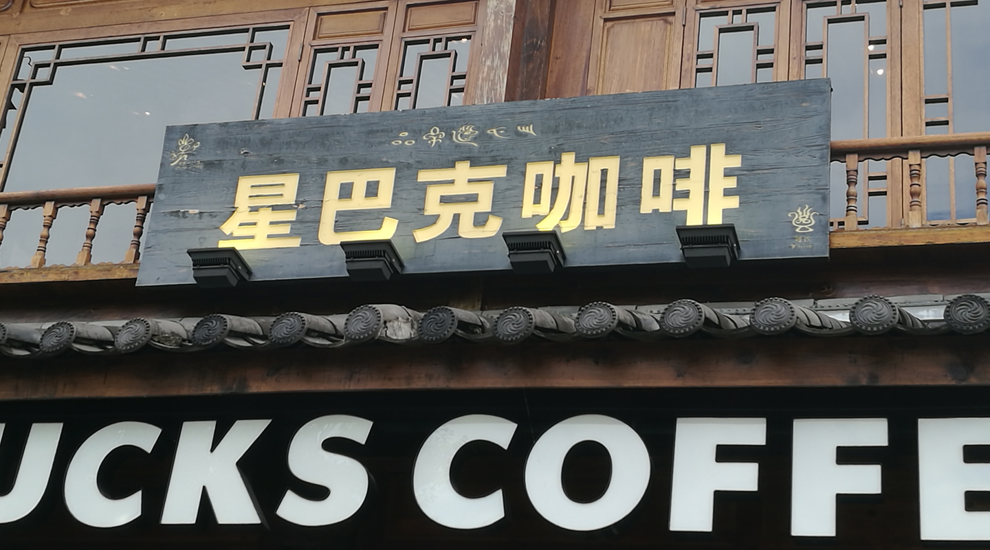 麗江一間咖啡店的門戶，招牌上方刻有品牌的納西譯名，以東巴文寫成<em>（相片由受訪者提供）</em>