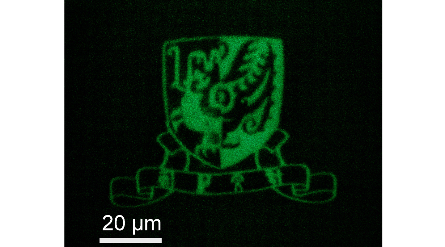 以石墨烯量子點打印而成的中大校徽，由聚焦顯微鏡拍攝。圖中白線長度代表二十微米，約為一根頭髮絲直徑三分一