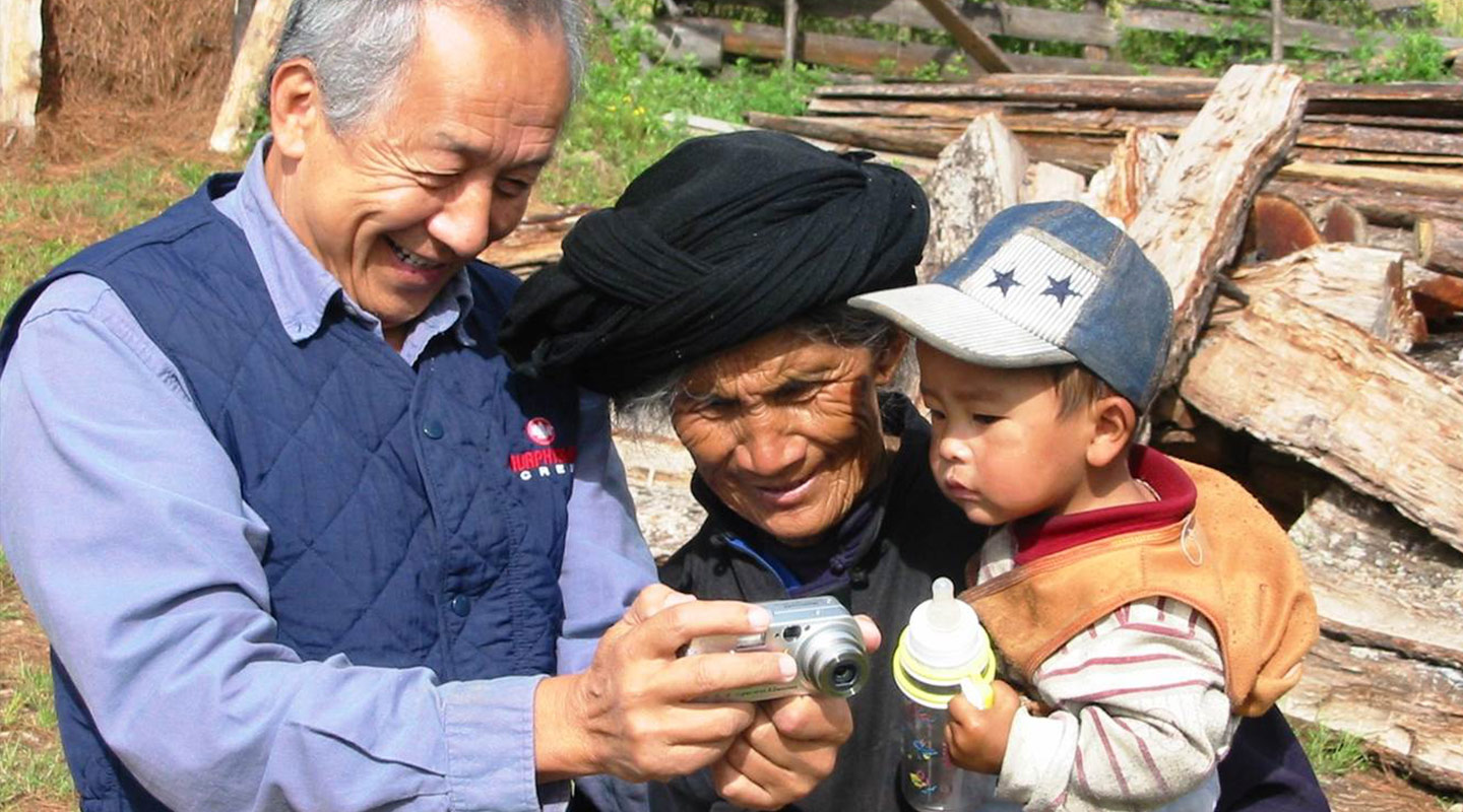 王士元教授探訪雲南普米族人，向一名婦人展示相片