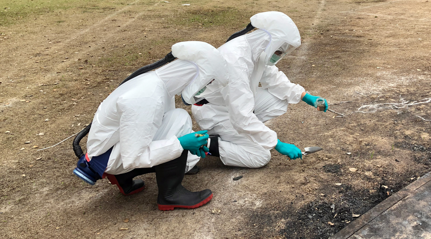 Professionals appointed by the University collecting soil samples at Sir Philip Haddon-Cave Sports Field in hazmat suits